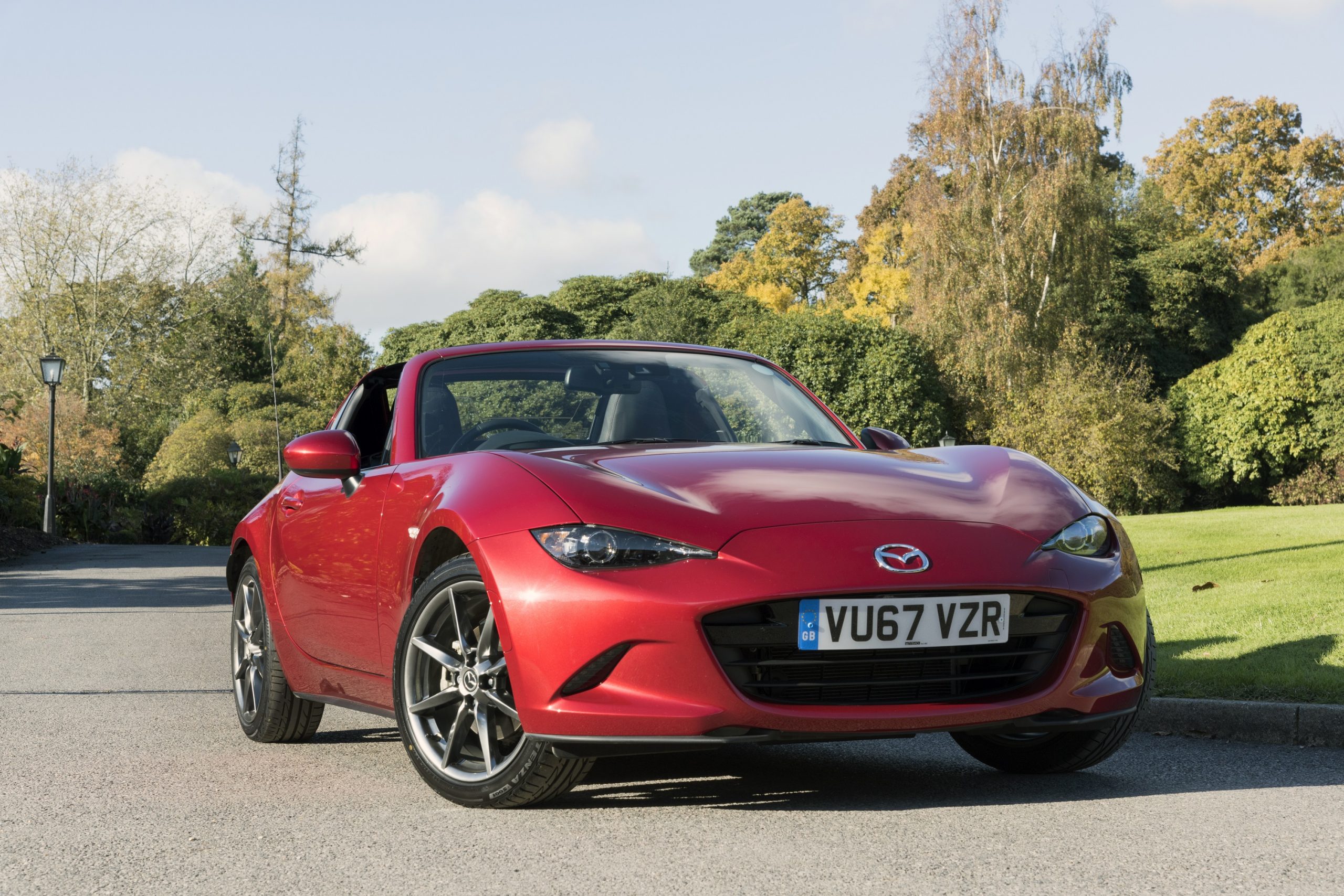 A red Miata RF shot from the front 3/4 on a concourse lawn