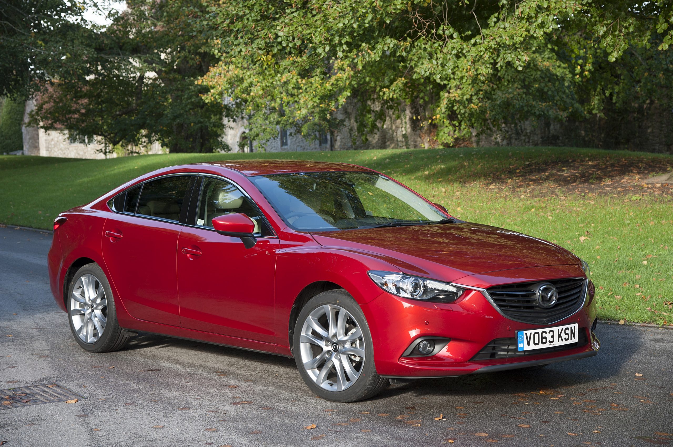 A red Mazda 6 sedan shot on a back road from the 3/4 angle