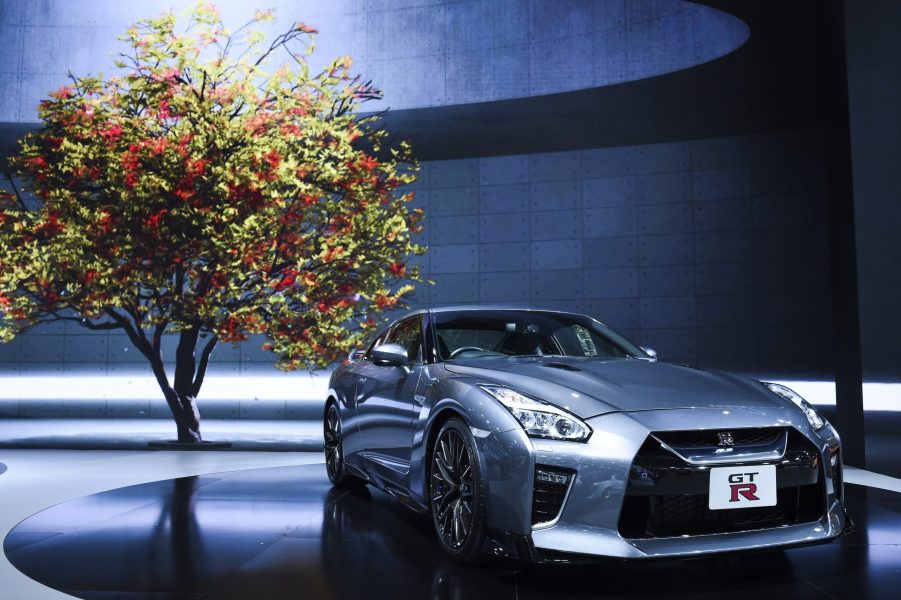 A silver Nissan GT-R shot from under a tree at an auto show