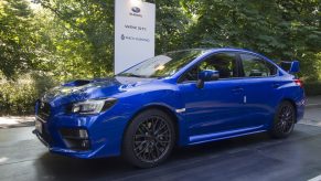 A blue Subaru WRX STI on a podium at an auto show, shot from the 3/4 angle