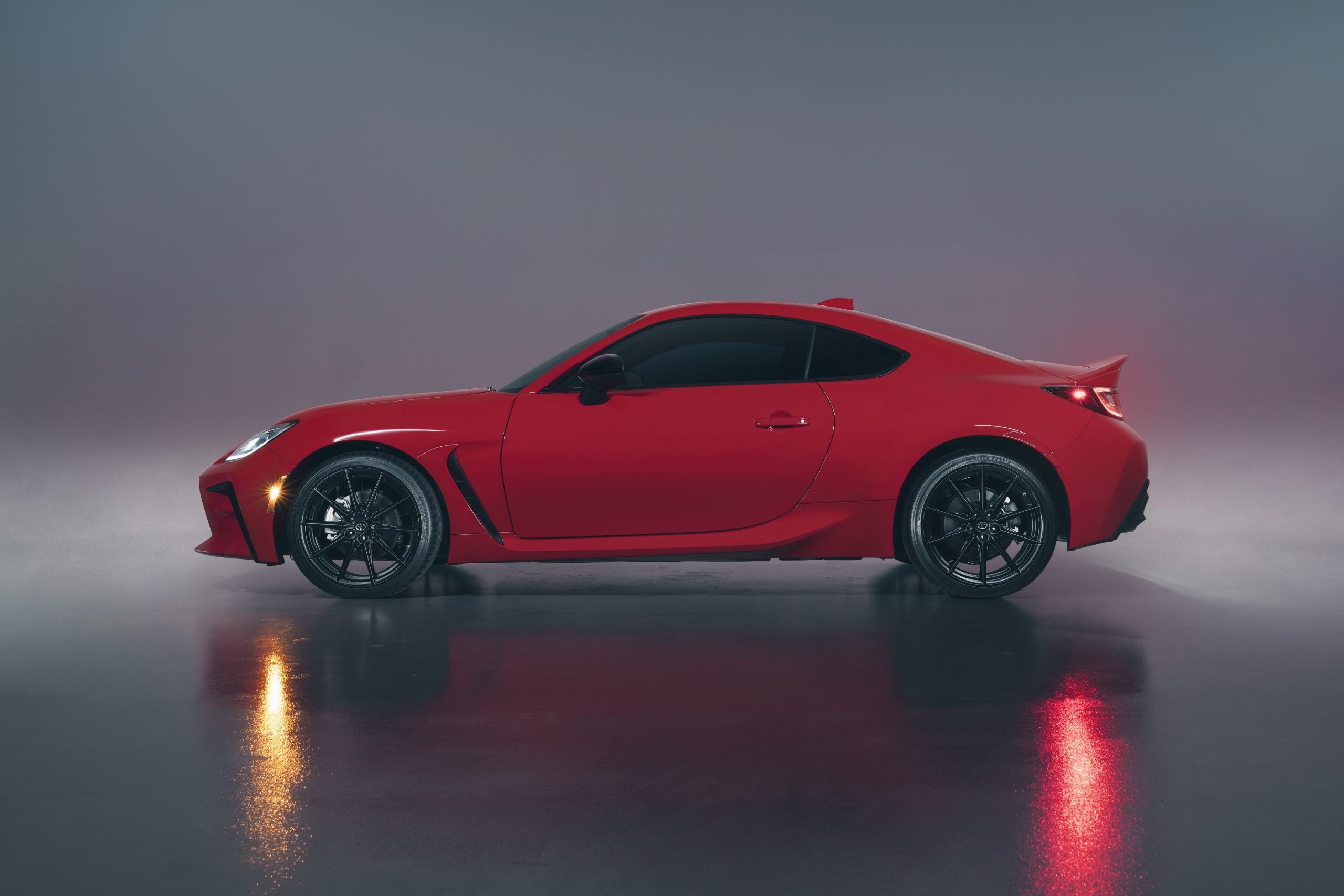 A red Toyota GR86 shot in profile in a photo studio