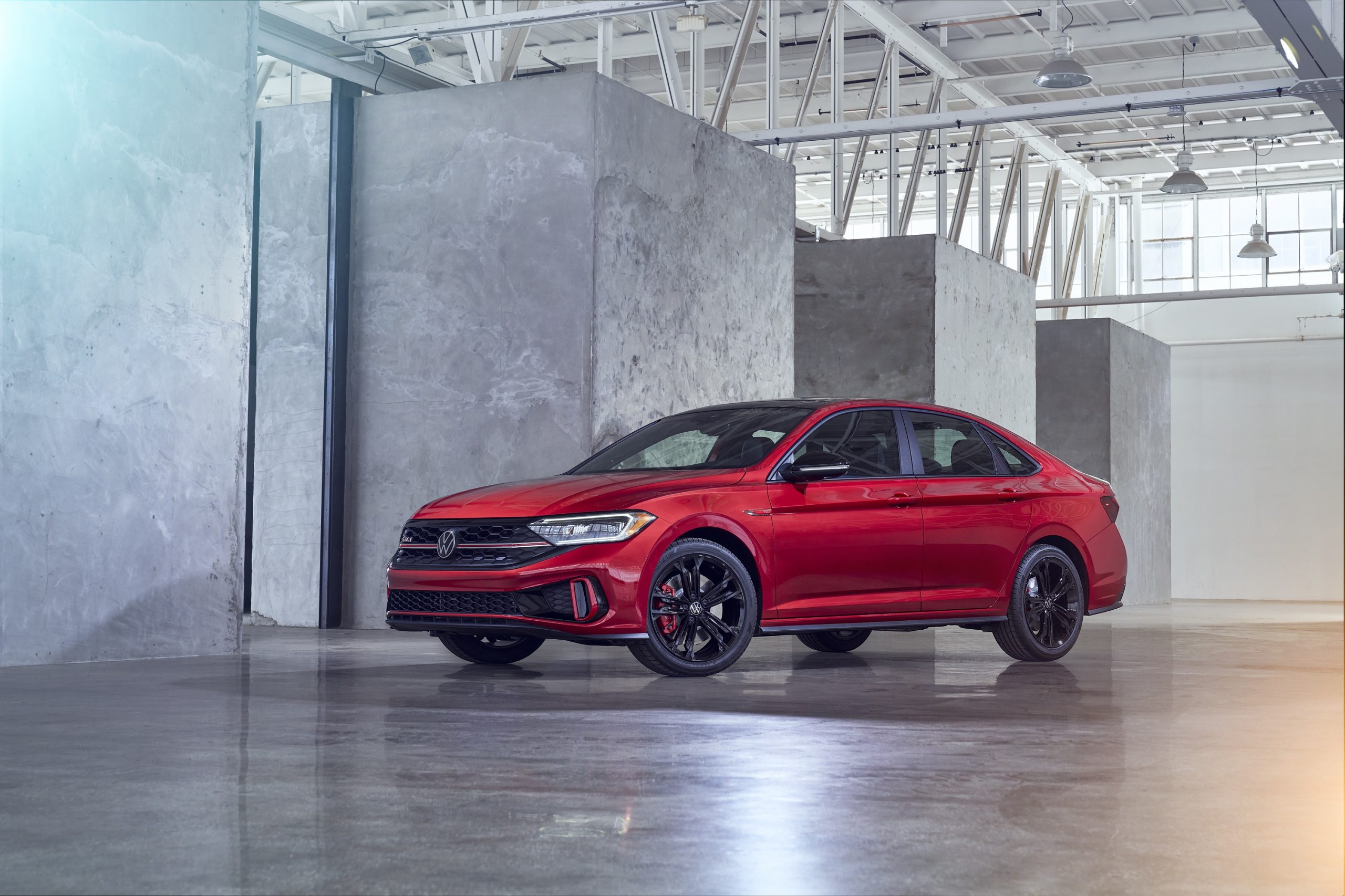 The Jetta GLI in red shot from the front 3/4 in a warehouse