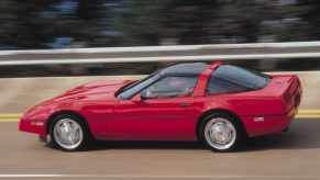 The side view of a red 1990 Chevrolet C4 Corvette ZR1 driving around a racetrack