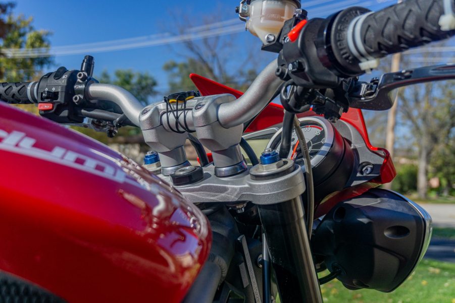 A close-up view of a red 2012 Triumph Street Triple R's aluminum handlebar with SW-MOTECH risers