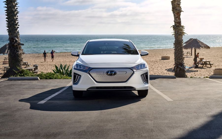 A 2021 Hyundai Ioniq Electric liftback with a white paint color option parked at a beach