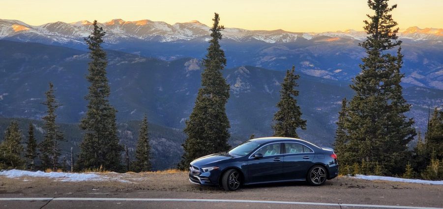 A Denim Blue Mercedes-AMG A35 sedan shot in profile on a mountain pass at sunset