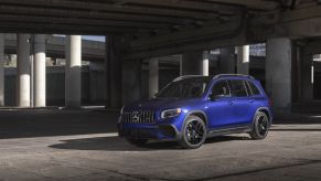 A 2021 Mercedes-Benz AMG GLB SUV with a blue paint color option parked under a concrete highway overpass