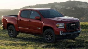 A red 2022 GMC Canyon parked in a valley with a backpacker walking by.