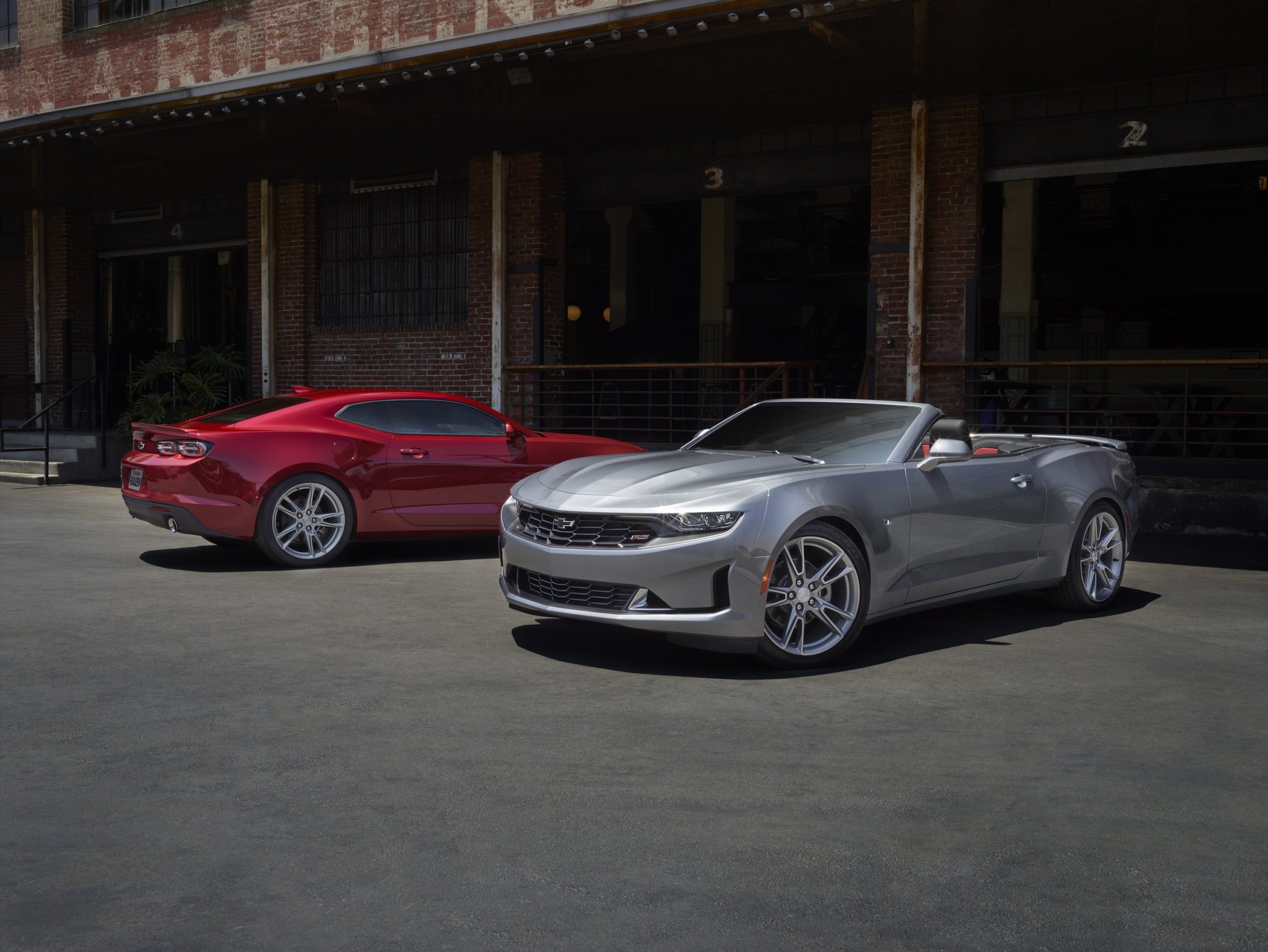 A pair of Camaro RS and LT models shot in front of a warehouse