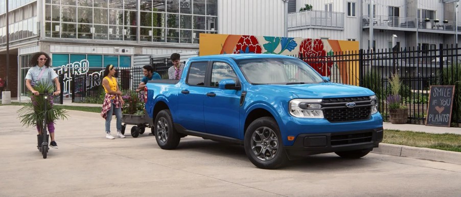 A blue 2022 Ford Maverick outisde with people around it.