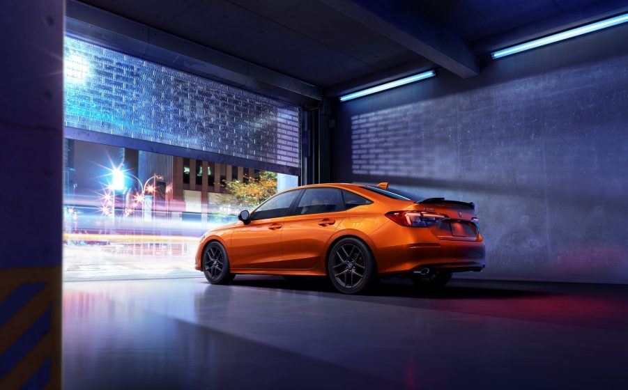 The rear 3/4 view of an orange 2022 Honda Civic Si in a garage