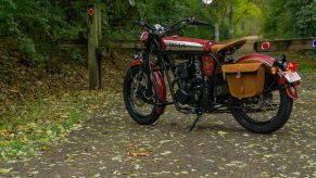 The rear 3/4 view of a red-and-chrome 2022 Janus Halcyon 250 on a forest path