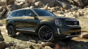 A green 2022 Kia Telluride against rocks.