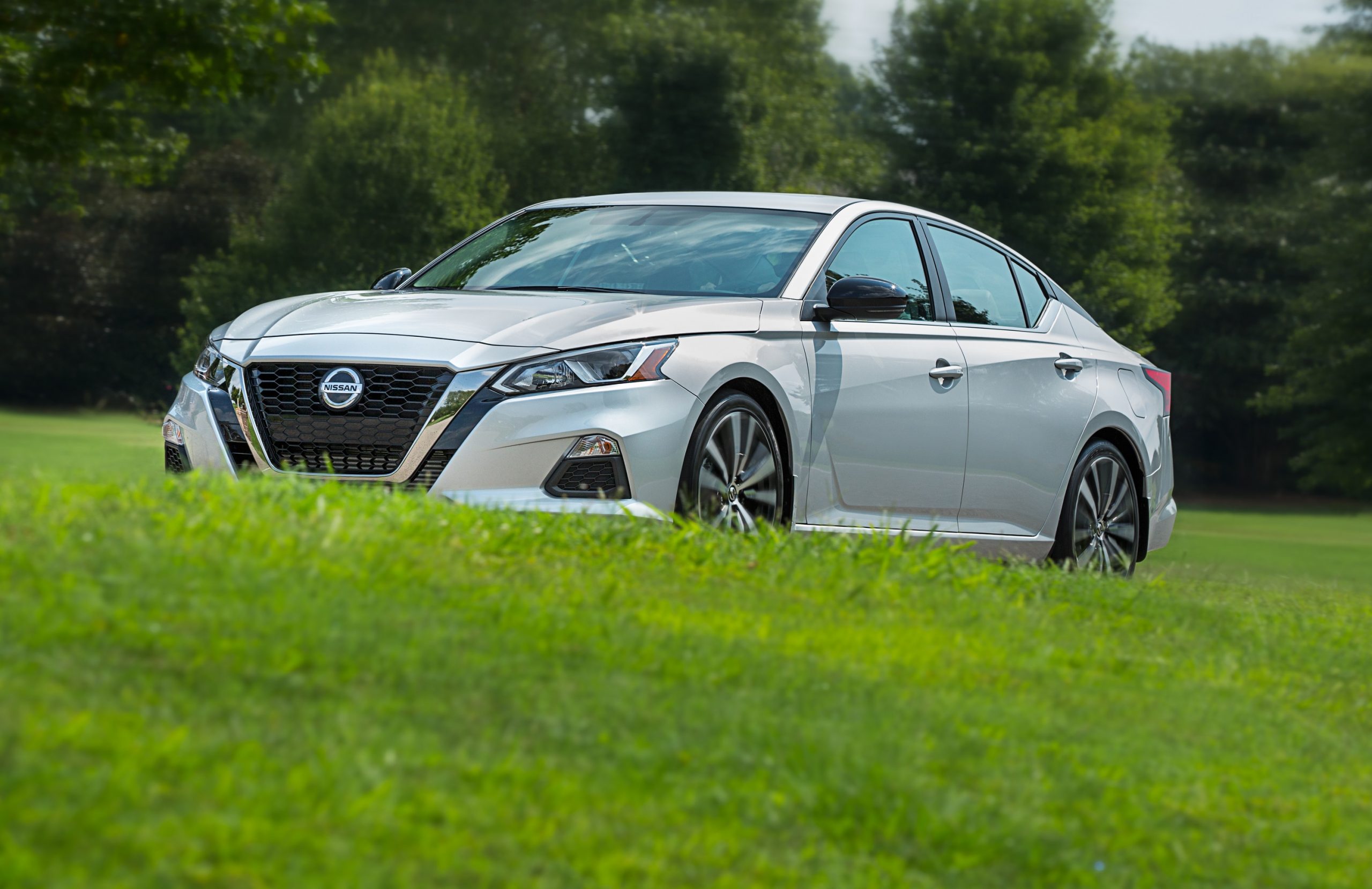 A silver 2022 Nissan Altima sedan shot from the front 3/4 on a grassy hill