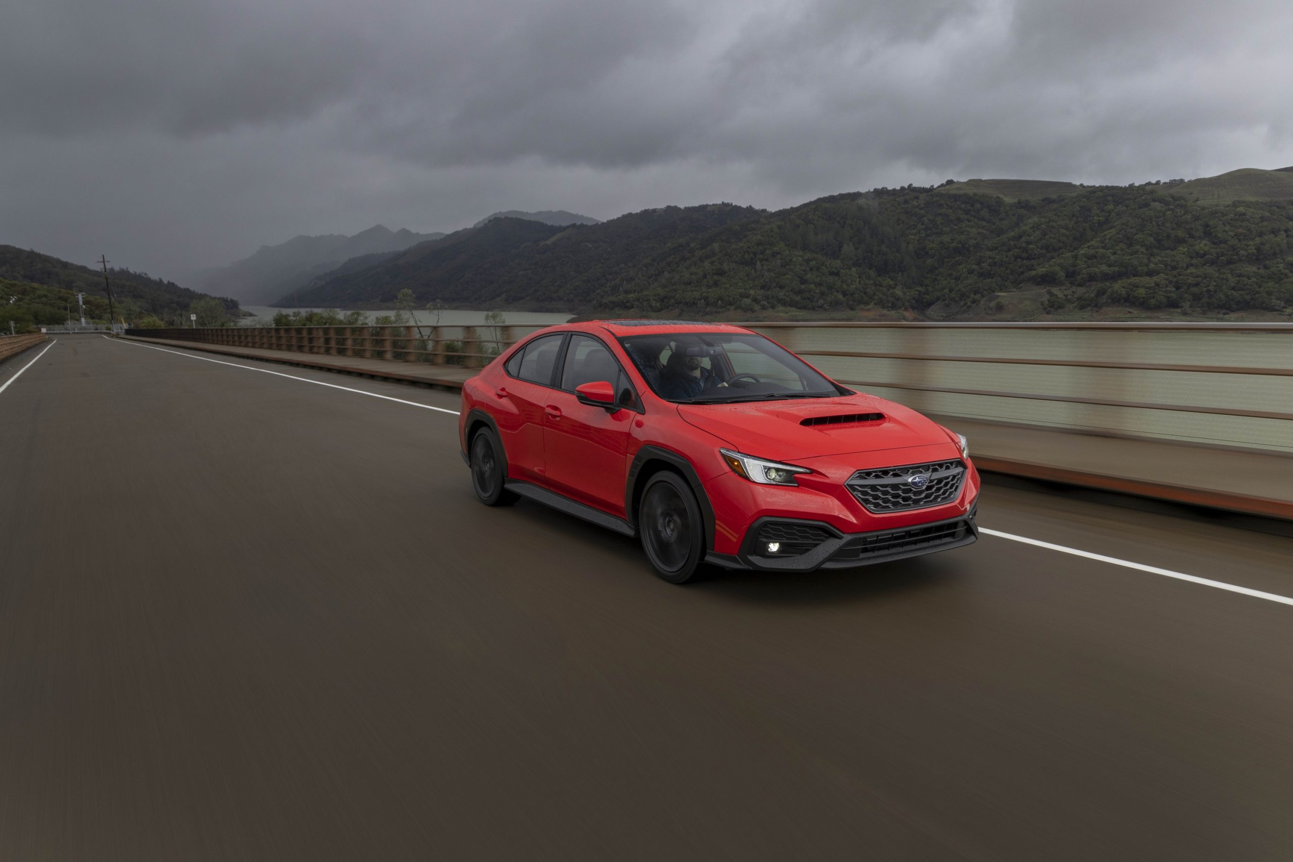 A red Subaru WRX shot from the front 3/4 on a rainy day