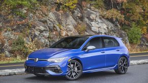 A blue 2022 Volkswagen Golf R parked by a rocky cliff