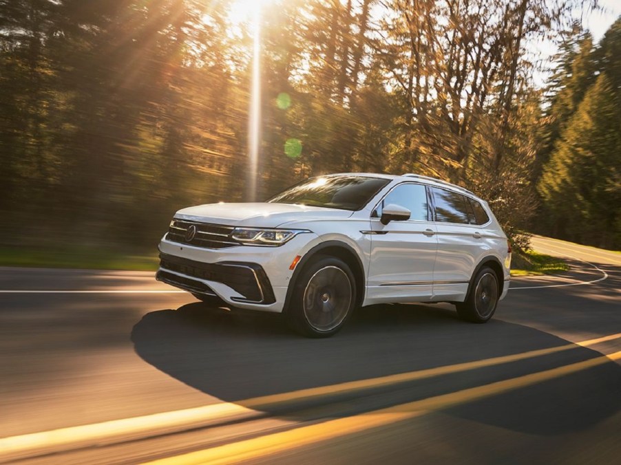 A white 2022 Volkswagen Tiguan driving down a sunny road.