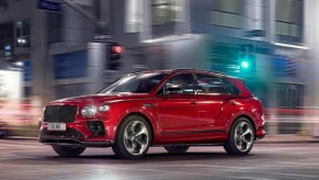 A red 2022 Bentley Bentayga driving with a city a blur in the background.