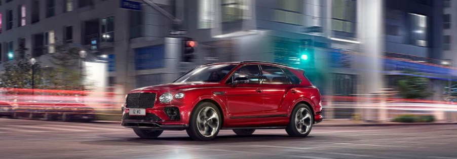 A red 2022 Bentley Bentayga driving with a city a blur in the background.