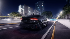 Black Sand Pearl 2022 Toyota Corolla driving on a city street at night