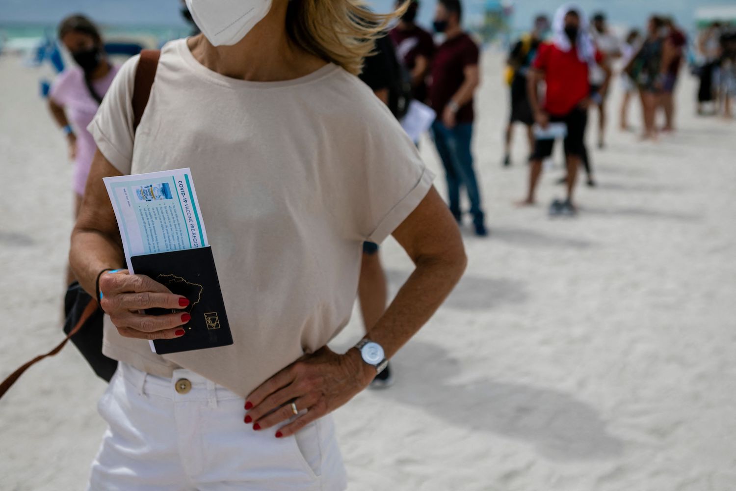 Traveler holding her passport waiting in line for a Corona Virus vaccine | EVA MARIE UZCATEGUI/AFP via Getty Images