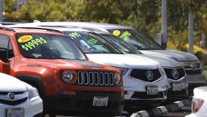 A selection of new and used cars with prices on their windshields at a dealer