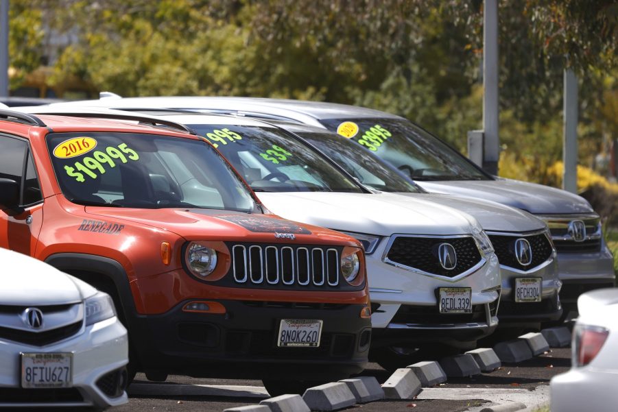 A selection of new and used cars with prices on their windshields at a dealer