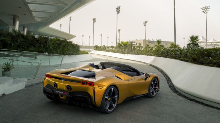 A Ferrari SF90 Spider plug-in hybrid (PHEV) convertible sports car with a yellow gold paint color option