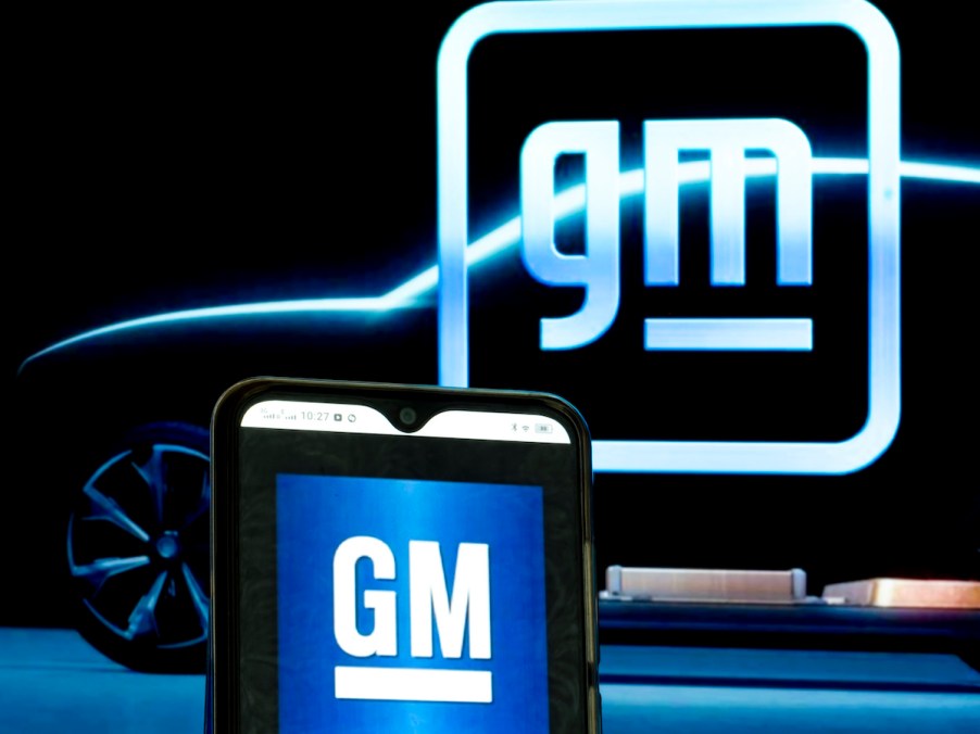 GM logos displayed on a smartphone and in the background