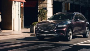 A dark colored 2022 Genesis GV70 parked in front of a store.