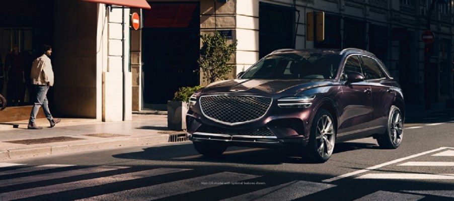 A dark colored 2022 Genesis GV70 parked in front of a store.