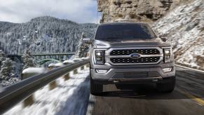 Gray 2022 Ford F-150, a truck with high gas mileage and fast acceleration, driving on a mountain road