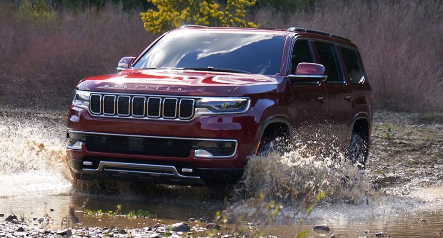 A red 2022 Jeep Wagoneer is driving through deep water.