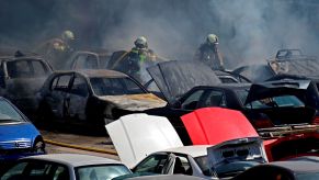 A depiction of a junkyard fire with firefighters and cars.