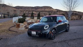 A racing green 2022 Mini Cooper JCW hot hatch shot from the front 3/4 at dusk in the Rockies