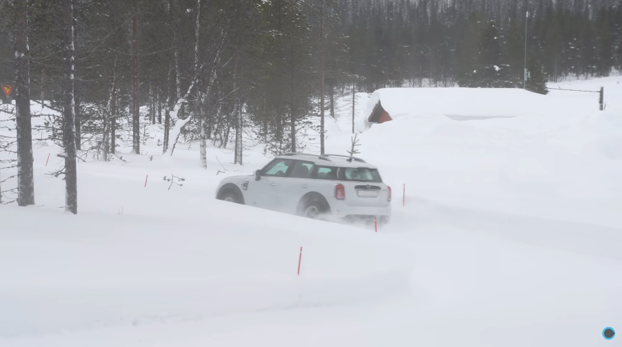 A white Mini Countryman drives through the snow to test out all-wheel drive vs. winter tires.