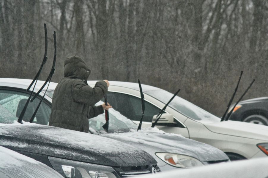 Person scraping ice off of a car windshield