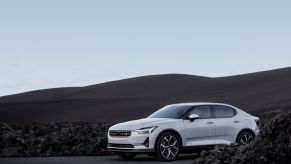 A white Polestar 2 with brown hills in the background.