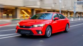 Rallye Red 2022 Honda Civic driving by a large modern building