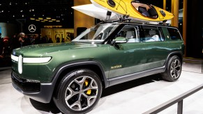 A green Rivian R1S electric SUV is on display.