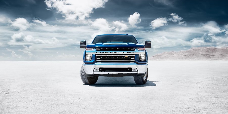 The front of a blue 2022 Chevy Silveado with clouds in the background