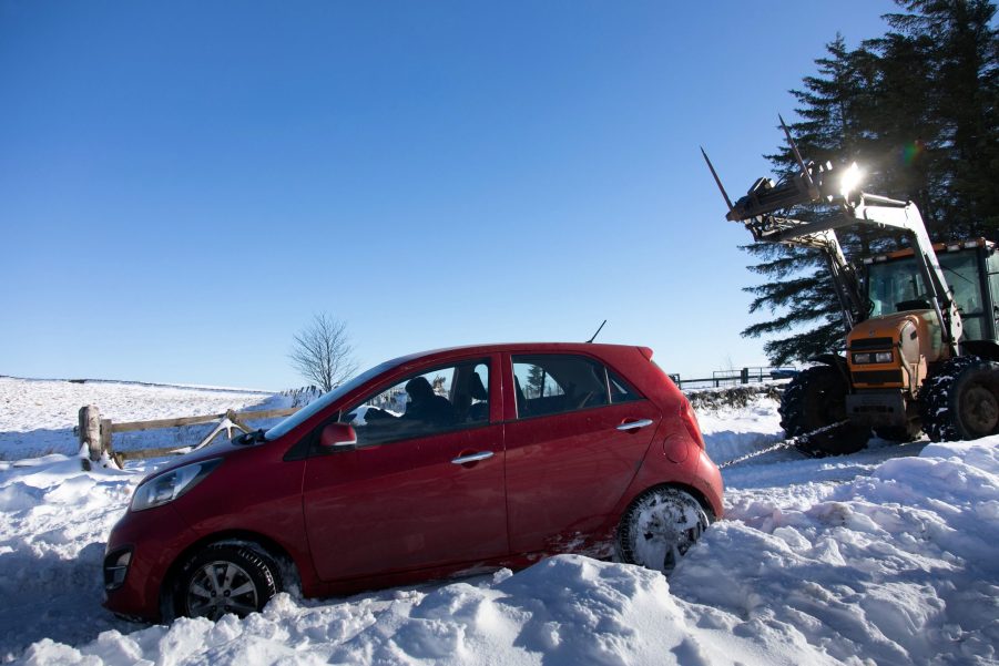 A stranded car being hauled out of a snow bank