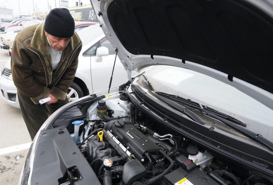 A man checks out the engine bay of a car