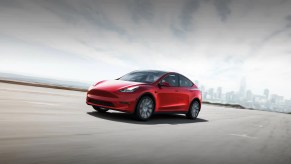 A red 2022 Tesla Model Y driving down a road.