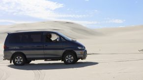 A green and gold JDM Mitsubishi Delica van shot in profile in the desert