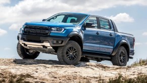 A blue 2021 Ford Ranger Raptor traversing a rocky terrain.