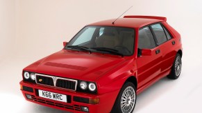 A red 1993 Lancia Delta Integrale hatchback in a white photo studio