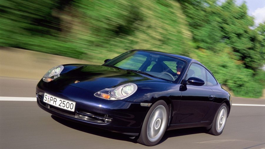 A dark-blue 1999 996 Porsche 911 Carrera drives down a road