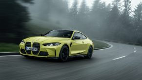 A yellow 2022 BMW M4 shot on a rainy day in the German woods