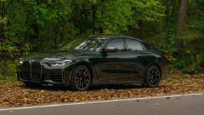 The front 3/4 view of a green 2022 BMW M440i xDrive Gran Coupe in a forest